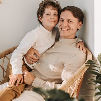 A father with his son sitting in a chair.