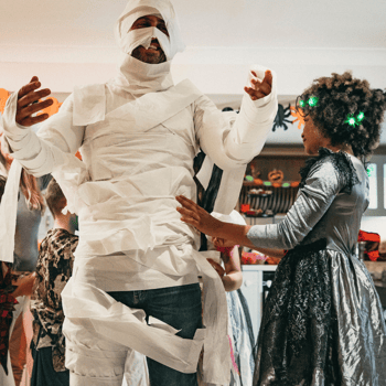 Little girl wrapping her dad in toilet paper like a mummy.
