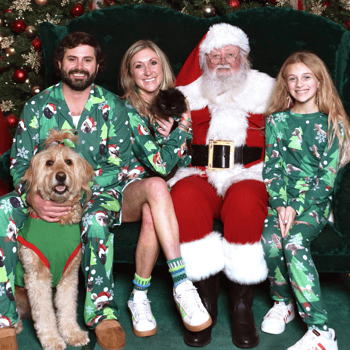 Family dressed in matching PJ's with their dog and cat and Santa.