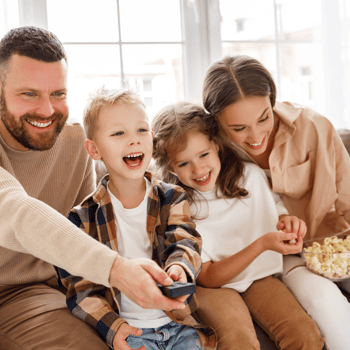 Family laughing and watching a movie together with popcorn.