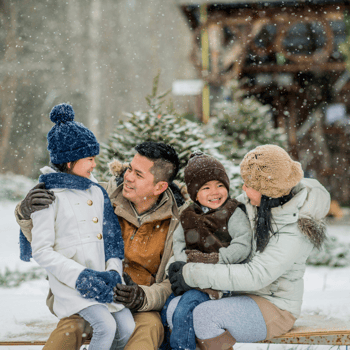 A family sitting outside in the snow cuddling together.
