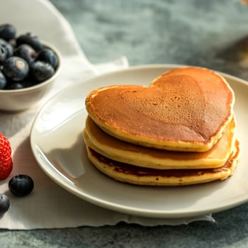 Heart shaped pancakes with blue berries.