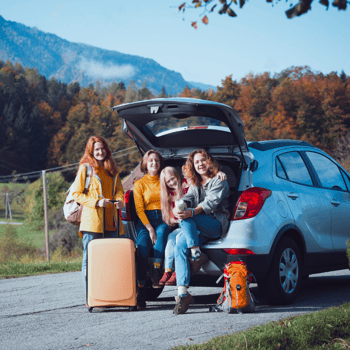 A family outside of the trunk of their car going on a road trip.