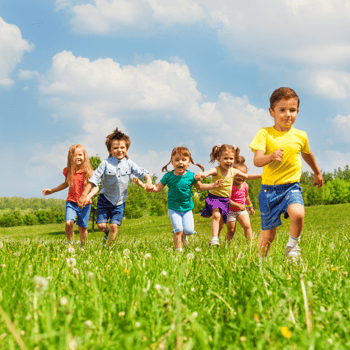 Kids running through a field during summer.