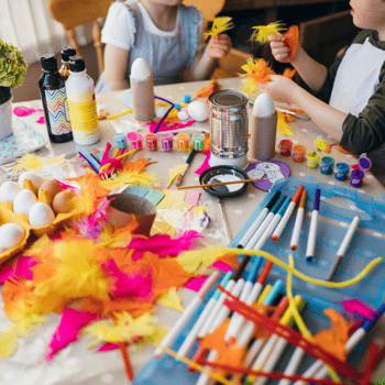 Kids doing spring crafts with colorful feathers, paint, markers, and pipe cleaners.