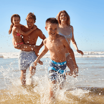 A family running through the ocean together.
