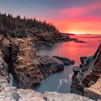 A sunset over a rocky mountain and the ocean.