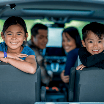 A family in the car together all smiling at the camera.
