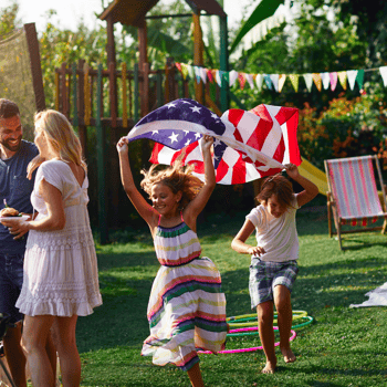 Kids running through the backyard with an American Flag.