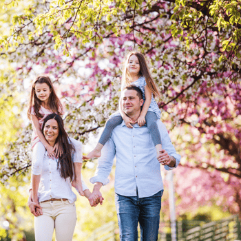 A family walking together in the spring with trees blossoming flowers.