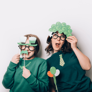 A mom and daughter dressed in green with green photo booth props