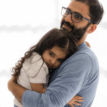 A dad hugging his little girl.