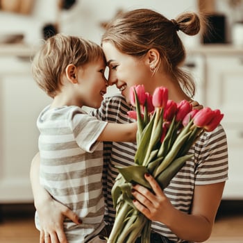 A little boy with his mom holding flowers.