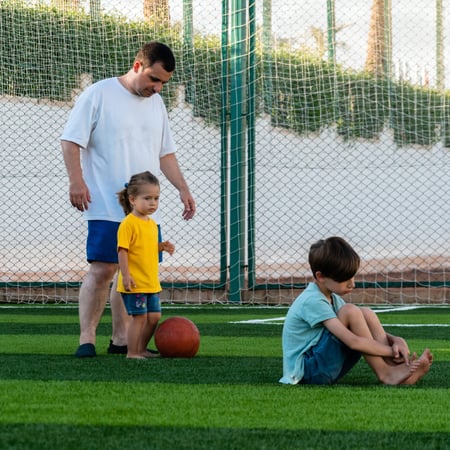 A dad and his kids playing soccer.