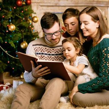 A family reading books by the Christmas tree.