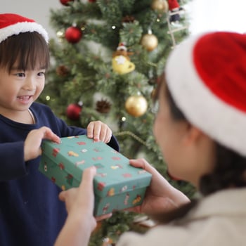 A little girl giving someone a Christmas gift.