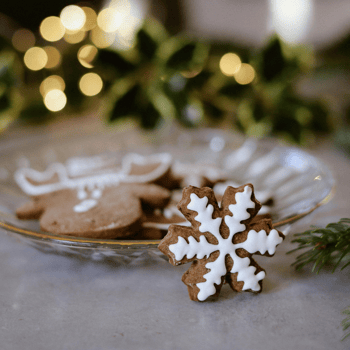 Snowflake Christmas cookie next to a plate with bokeh in the back.