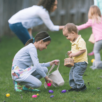 A little boy and little girl picking up plastic easter eggs in a backyard.