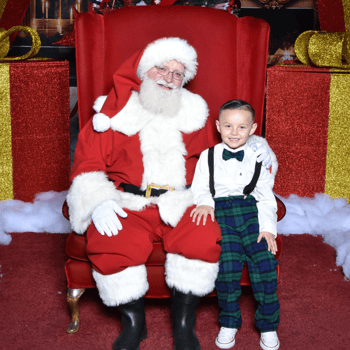 A little boy sitting with Santa Claus.