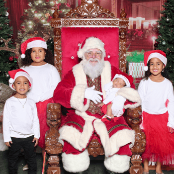 Baby sleeping in Santa's arms surrounded by her siblings.