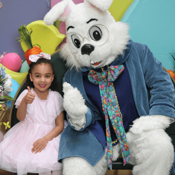 A little girl giving a thumbs up with the Easter Bunny.