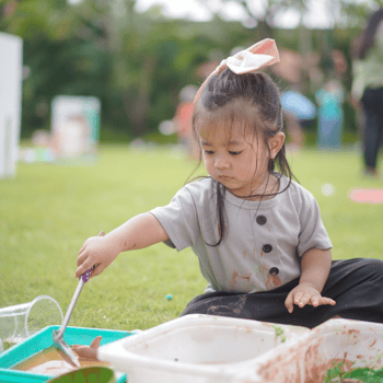 A little girl playing outside with a water sensory bin.