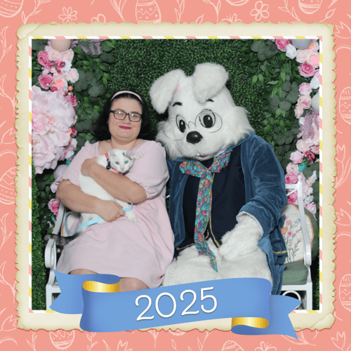 Woman in a pastel pink dress holding her cat and posing with the Easter Bunny