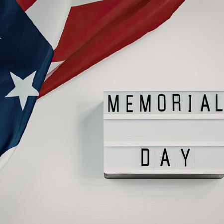 A sign that says Memorial Day with an American Flag in the corner.