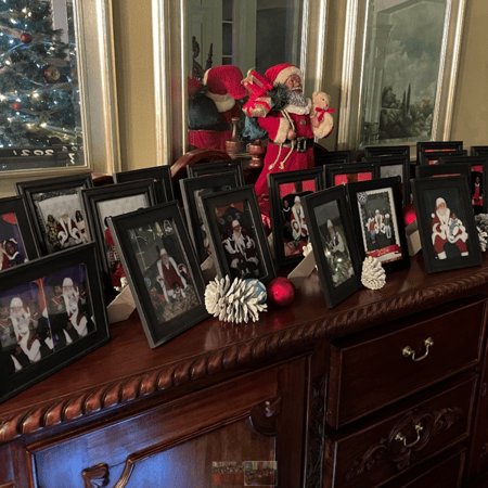 25 years of framed Santa photos on a cabinet.