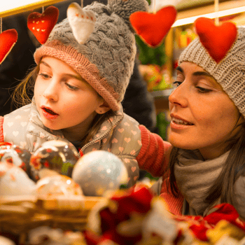 A mother and daughter looking at ornaments at a Christmas market.