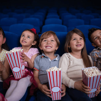 Kids sitting together with popcorn watching a movie.