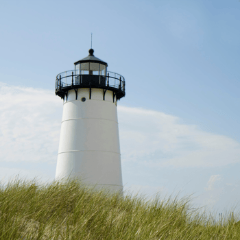 A black and white lighthouse on a hill.