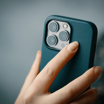 A woman holding an Iphone with the camera lenses showing.
