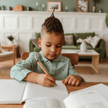 A little boy doing his homework at a table.