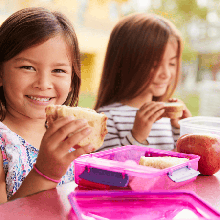 Two little girls eating lunch together.