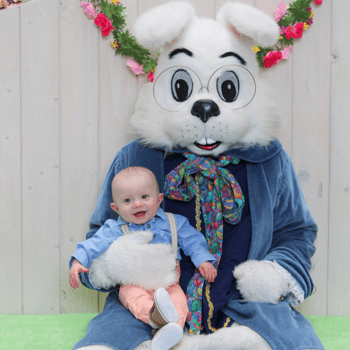 A baby boy sitting with the Easter Bunny smiling.
