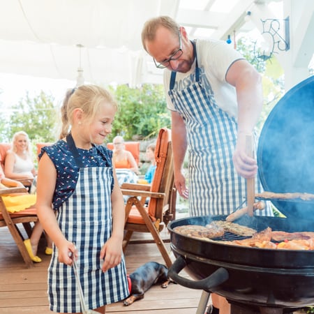 A dad and his daughter grilling together.