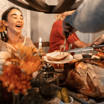 A lady laughing while someone puts turkey on her plate.