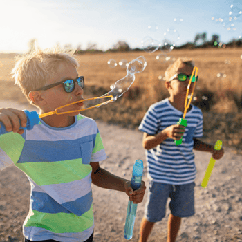 Two boys blowing bubbles on a sunny day.