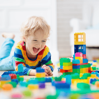 A little boy playing with legos on the floor.