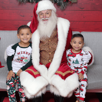 Two little boys wearing Christmas pjs with Santa.