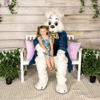 A little girl sitting with the Easter bunny smiling.