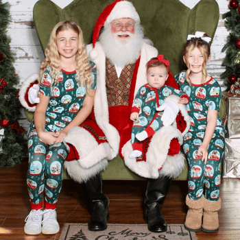 Three little girls wearing matching Pjs with Santa.