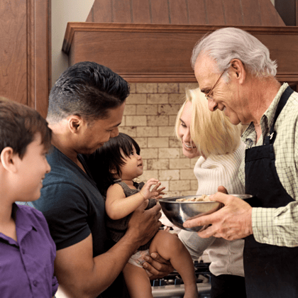 Family playing with a baby while cooking a meal.