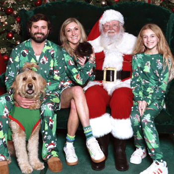 A family in matching pjs with their pets and Santa.