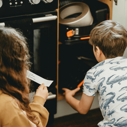 A little boy and girl doing a scavenger hunt and reading a clue.