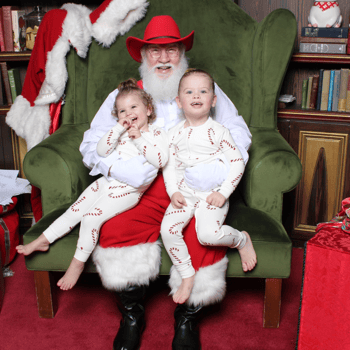 A little girl and little boy giggling with Santa wearing matching Pjs