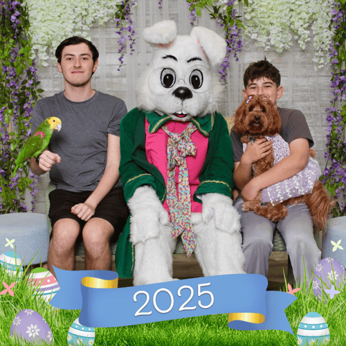 Two boys, one holding a bird and one holding a dog, sitting with the Easter Bunny