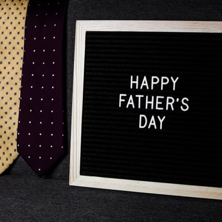 A sign that says Happy Father's Day with ties in the background.
