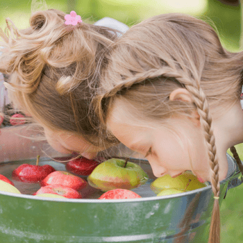 Two girls bobbing for apples.